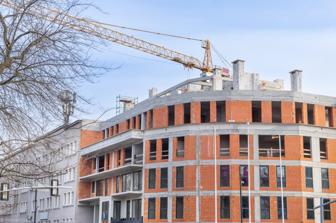 Żuraw budowlany nad nowo powstającym budynkiem o zaokrąglonej elewacji