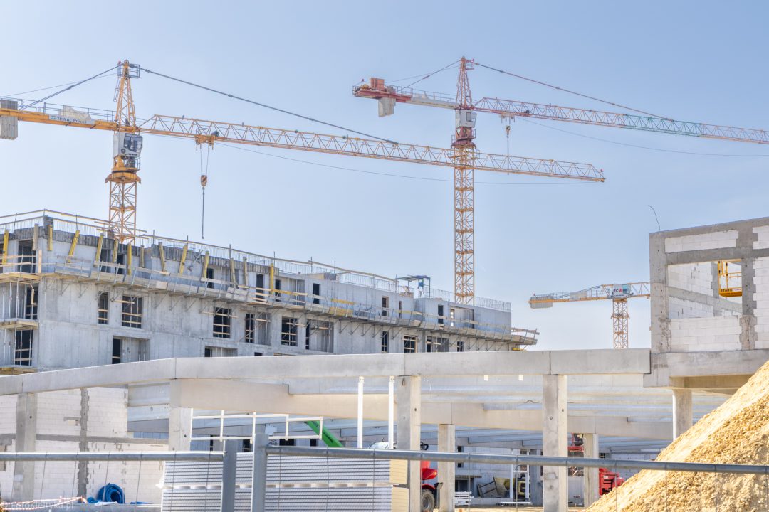 Powstające budynki mieszkalne i żuraw budowlany na placu inwestycji