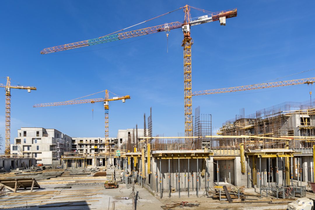 Powstające budynki mieszkalne i żuraw budowlany na placu inwestycji