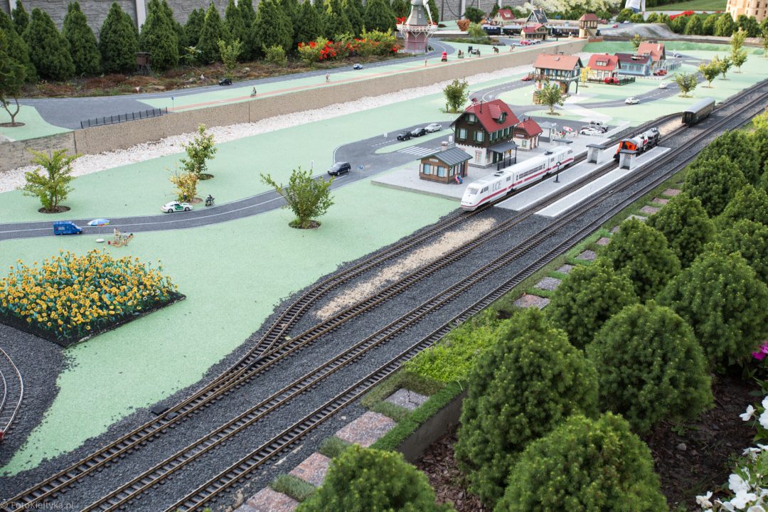 Miniaturowy port z zacumowanym statkiem, nabrzeżem i torami.