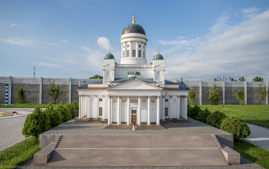 Miniatura białej katedry z kolumnowym portykiem i zieloną kopułą.